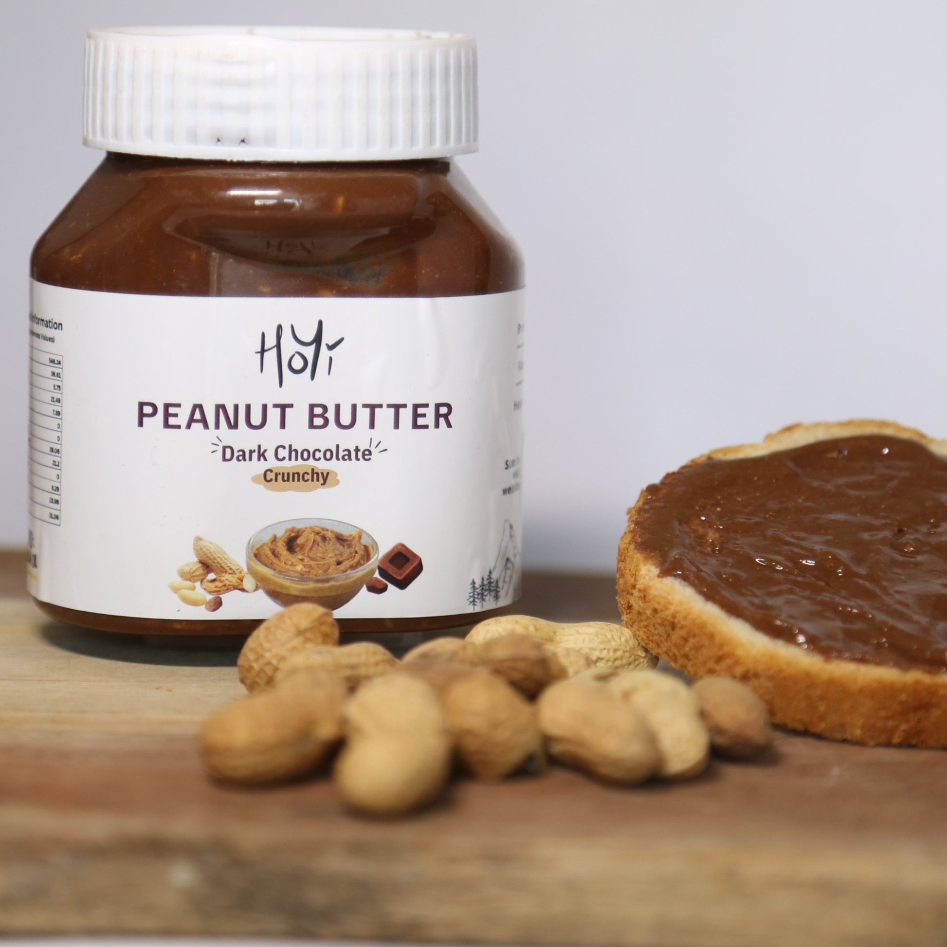 Jar of HoYi Dark Chocolate Crunchy Peanut Butter with peanuts and a toast spread with the peanut butter

